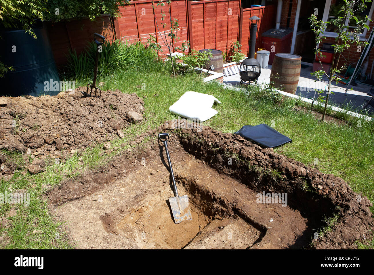 digging a hole to build a pond in a garden in the uk with pond liner and protective liner Stock Photo