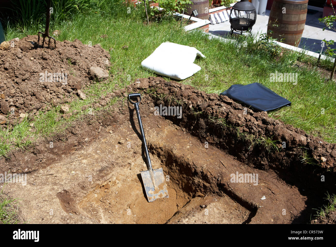 digging a hole to build a pond in a garden in the uk with pond liner and protective liner Stock Photo