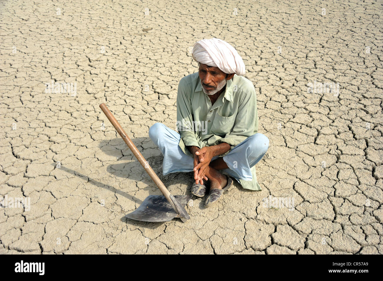 Farmer sitting on dried loamy soil, Basti Lehar Walla village, Punjab, Pakistan, Asia Stock Photo