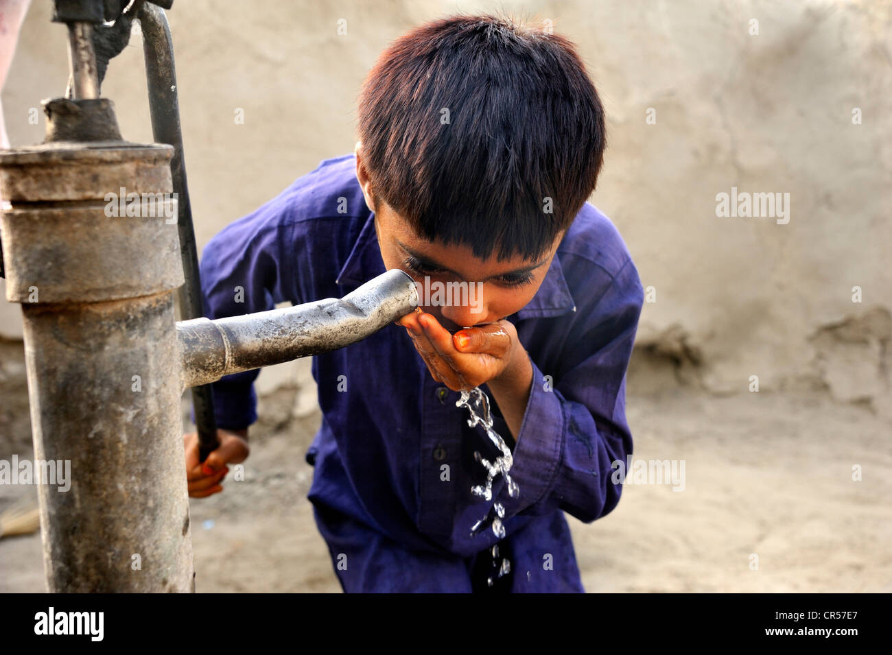 Boy drinking water from a well with a hand pump, village of Basti Lehar Walla, Punjab, Pakistan, Asia Stock Photo