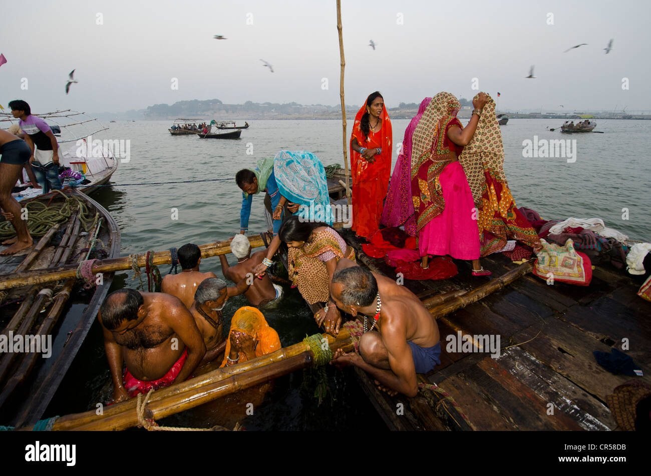 Pilgrims taking their holy dip in the water at Sangam, the confluence of the holy rivers Ganges, Yamuna and Saraswati, in Stock Photo