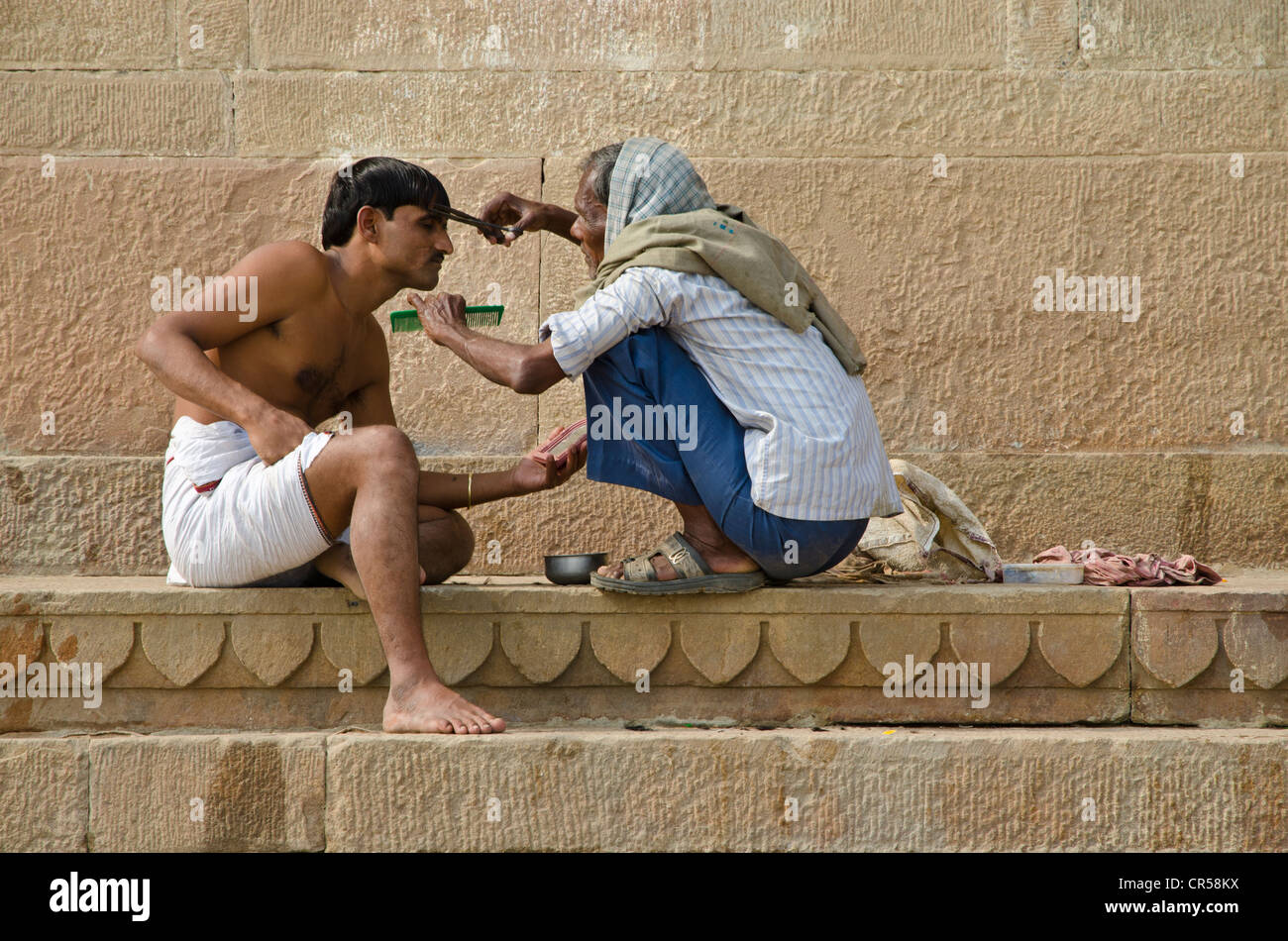 Hairdresser cutting hair at the ghats of Varanasi, Uttar Pradesh, India, Asia Stock Photo
