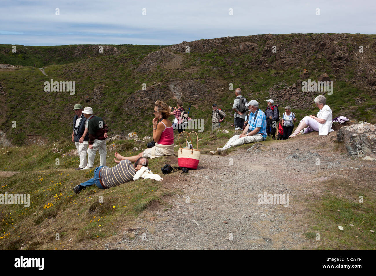 Holidaymakers sitting on clifftops at Kynance Cove Stock Photo