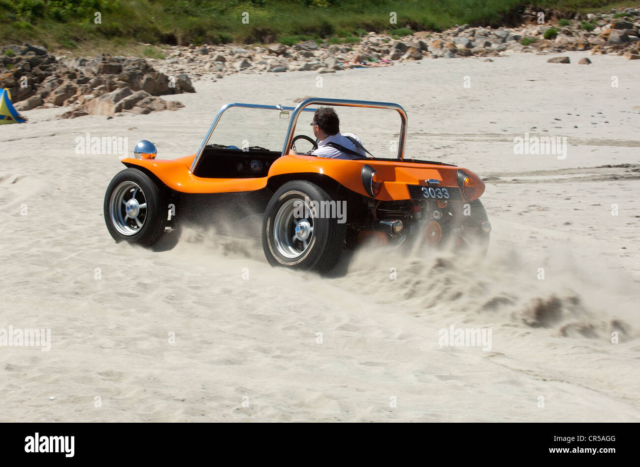 VW beach buggy driving on a sandy beach under a blue sky Stock Photo