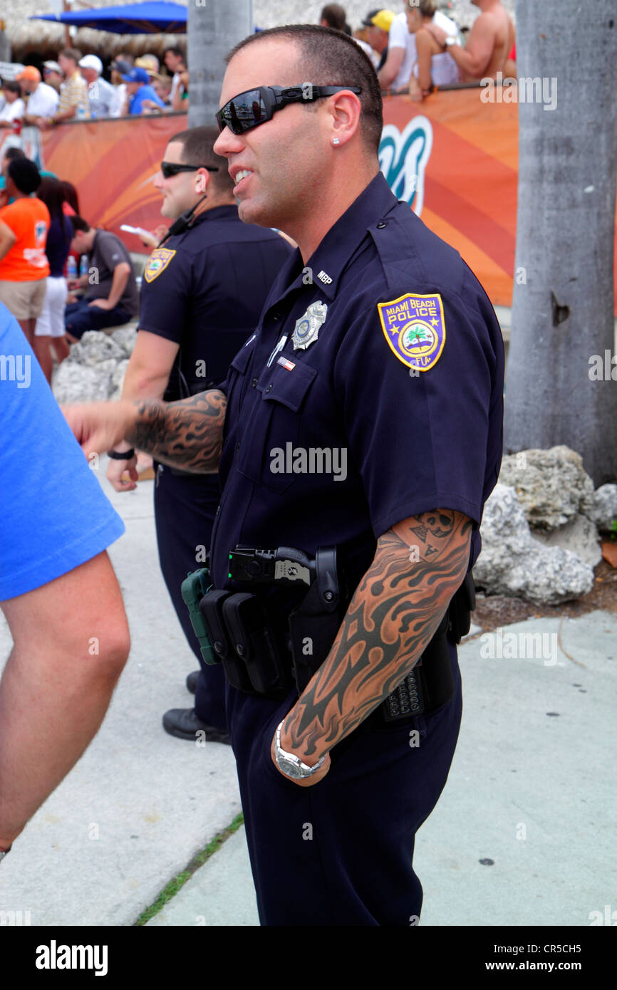 Miami Beach Florida,police,policeman,tattoo,arm,uniform,pierced ear,earring,sunglasses,FL120525013 Stock Photo