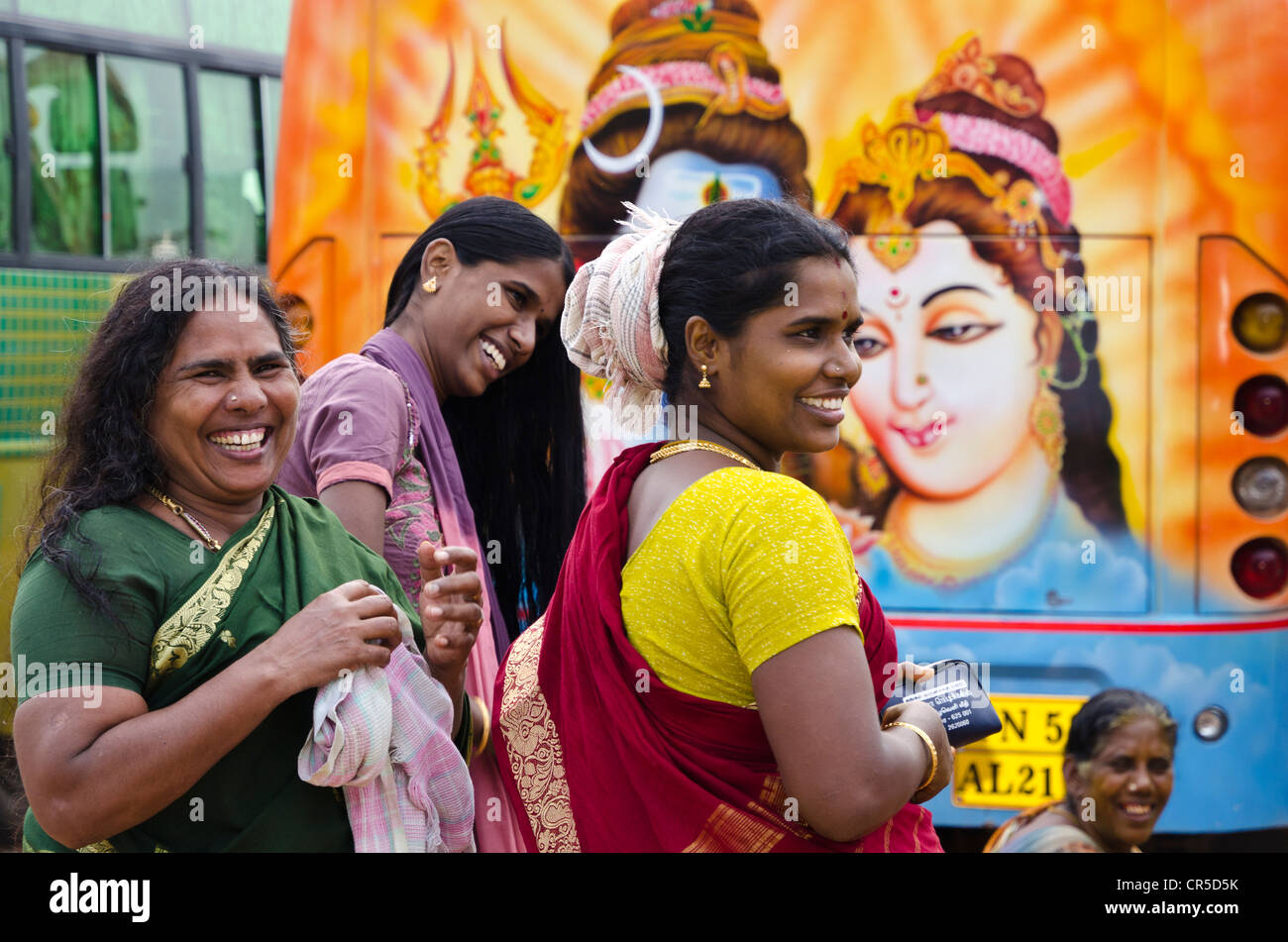 Young ladies on pilgrimage having fun doing their make up behind a painted bus outside the Ramanathaswamy Temple in , India Stock Photo