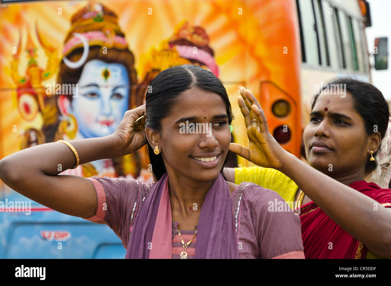 Young ladies on pilgrimage having fun doing their make up behind a painted bus outside the Ramanathaswamy Temple in , India Stock Photo