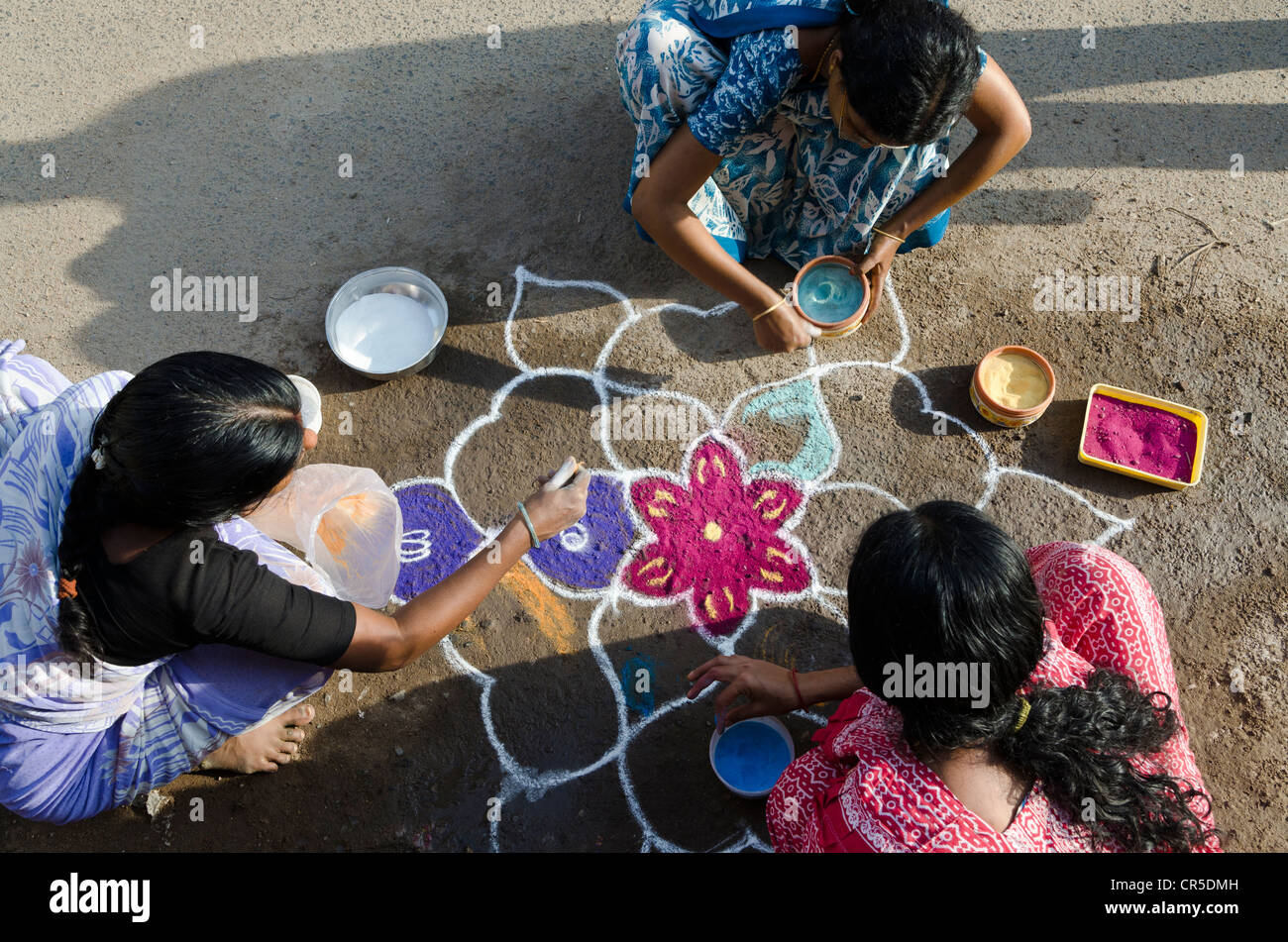Women making Rangoli, decorative sand designs in the streets of Madurai during a Hindu festival, meant as sacred welcoming area Stock Photo