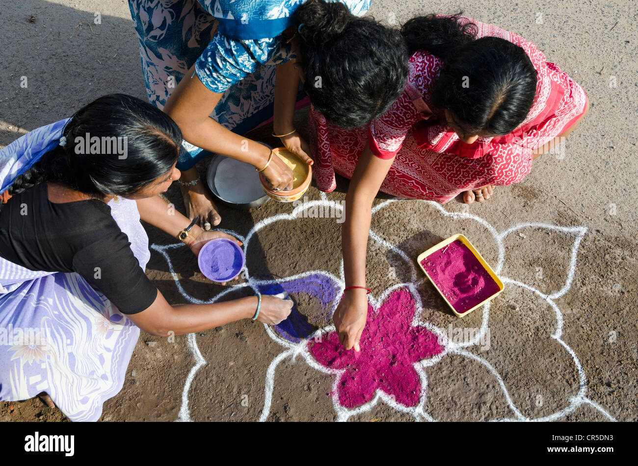 Women making Rangoli, decorative sand designs in the streets of Madurai during a Hindu festival, meant as sacred welcoming area Stock Photo