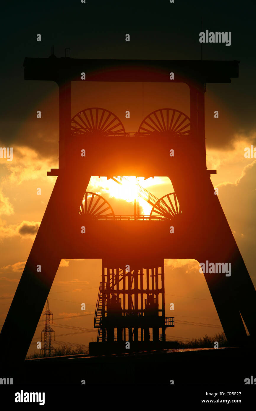 Winding tower of a former coal mine, sunset, dark sky, clouds. Symbol for the end of the coal mining in the Ruhr area, Germany. Stock Photo