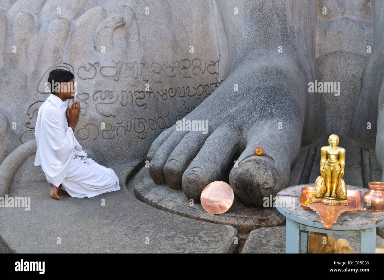Jain pilgrim is praying at the feet of the gigantic statue of