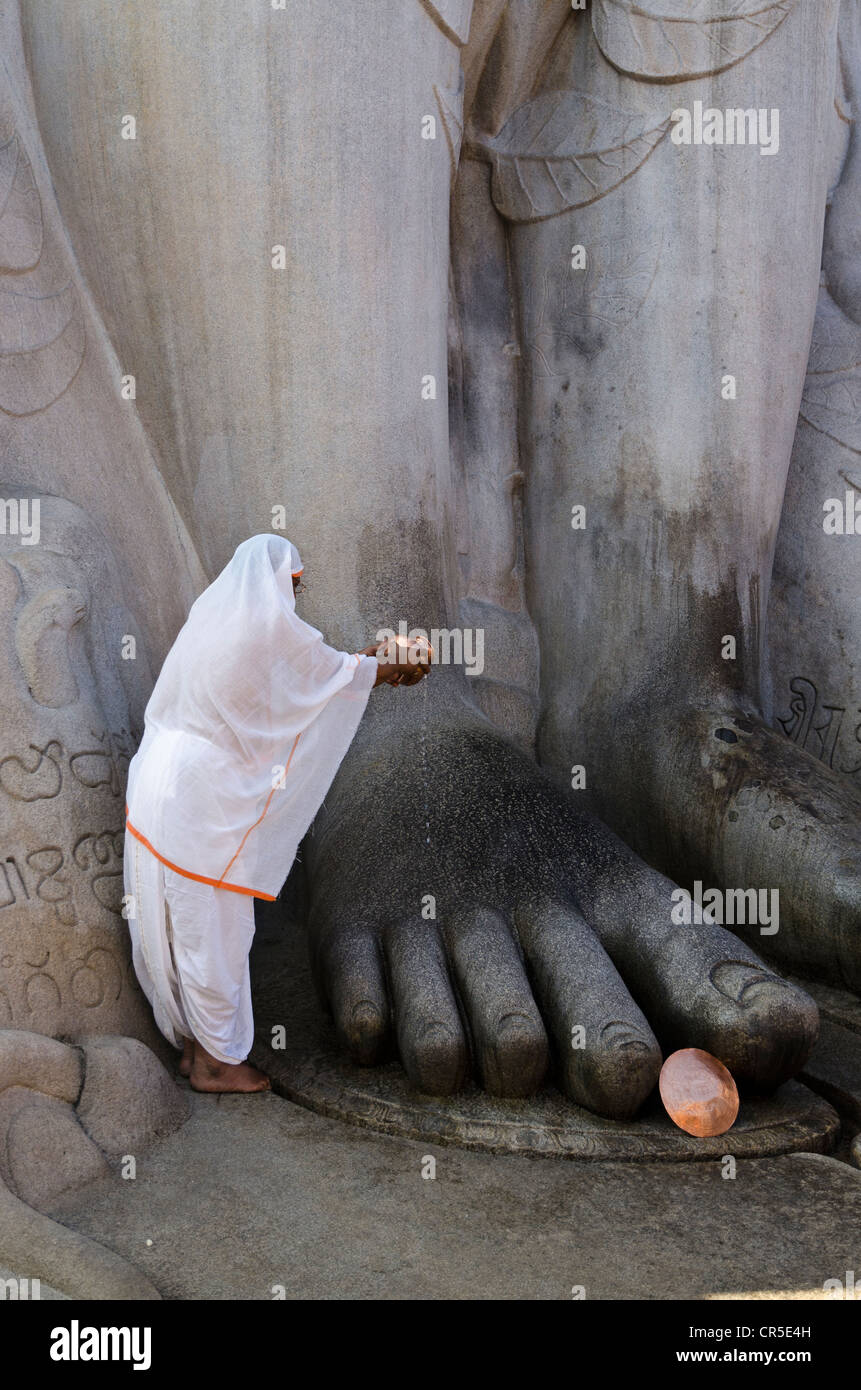 Jain pilgrim is pouring water on the feet of the gigantic statue of Gomateshwara in Sravanabelagola, Karnataka, India, Asia Stock Photo