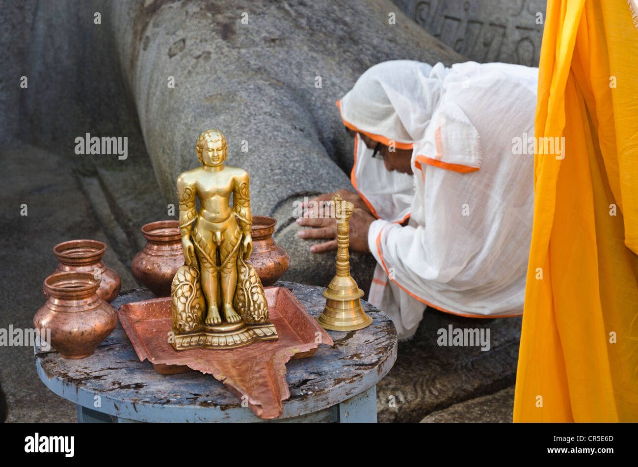 Jain pilgrim is praying at the feet of the gigantic statue of