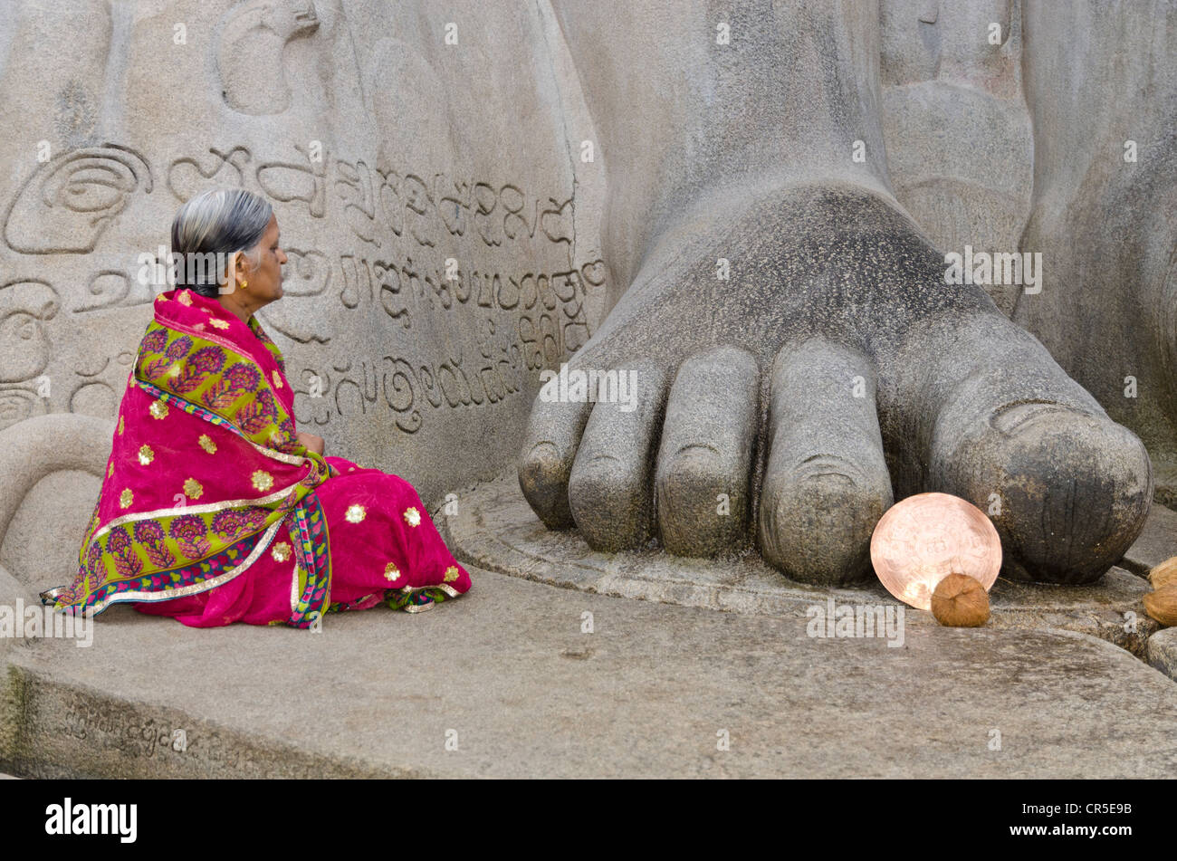 Female Jain pilgrim meditating at the feet of the statue of Lord