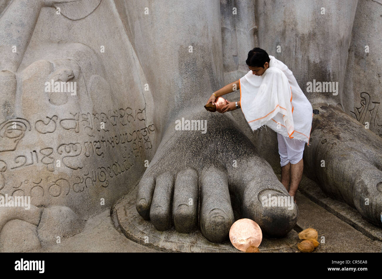 A Jain pilgrim is pouring water over the feet of the statue of Lord
