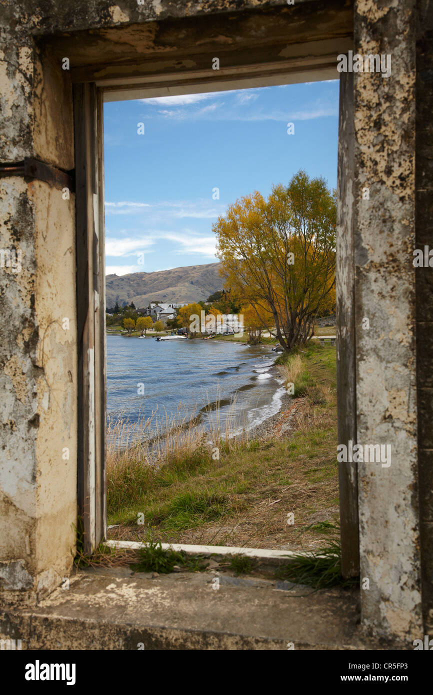 Looking through window of derelict building to Lake Dunstan and Old Cromwell Town, Cromwell, Central Otago, New Zealand Stock Photo