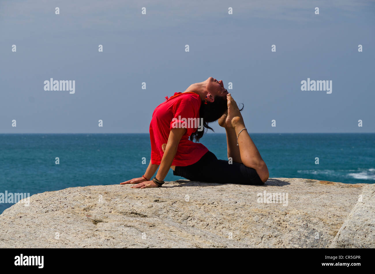 Woman in a yoga position, Bhujangasana, by the sea in Kanyakumari, Tamil Nadu, India, Asia Stock Photo