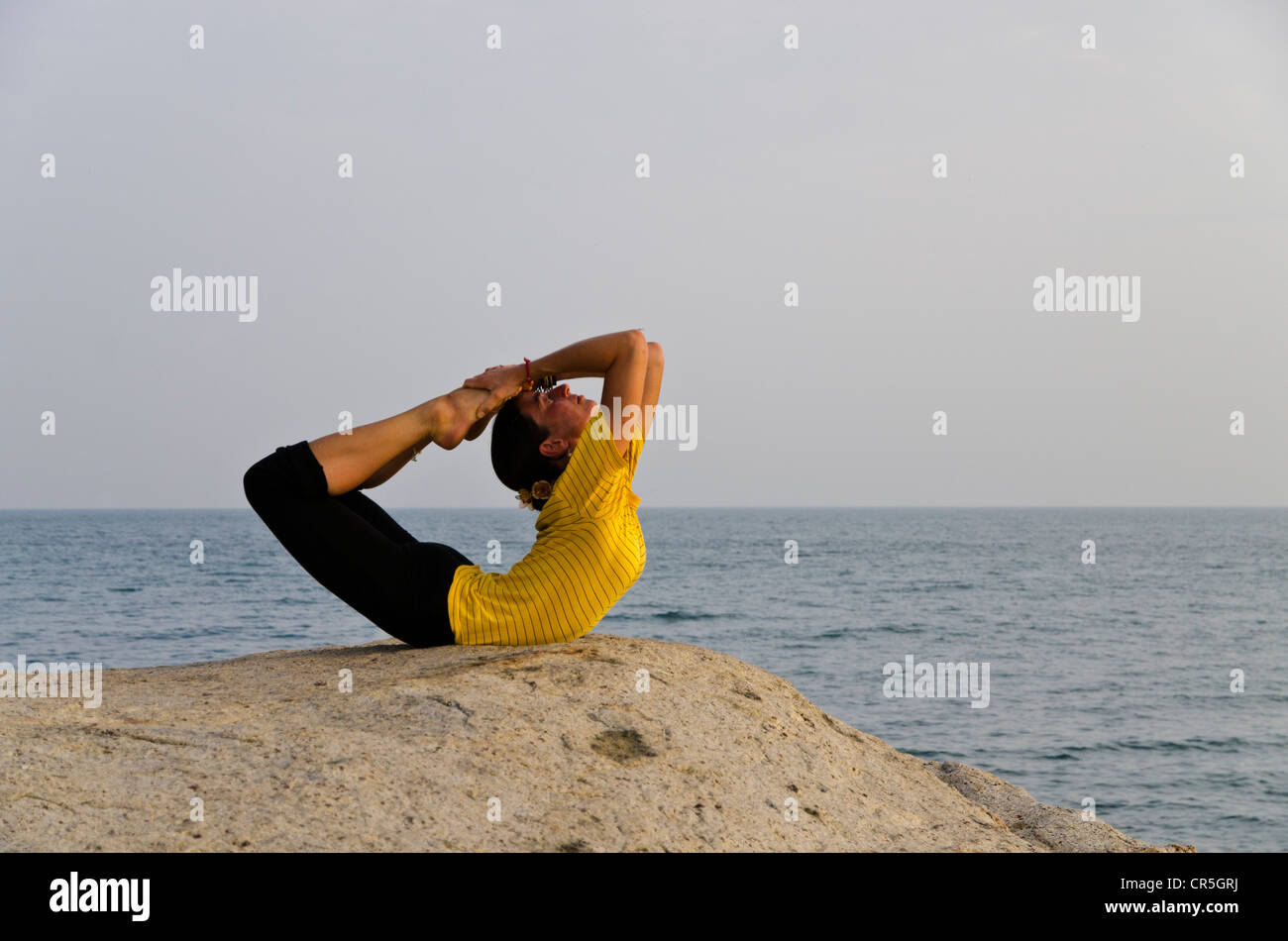 Woman in a yoga position, Dhanurasana, by the sea in Kanyakumari, Tamil Nadu, India, Asia Stock Photo