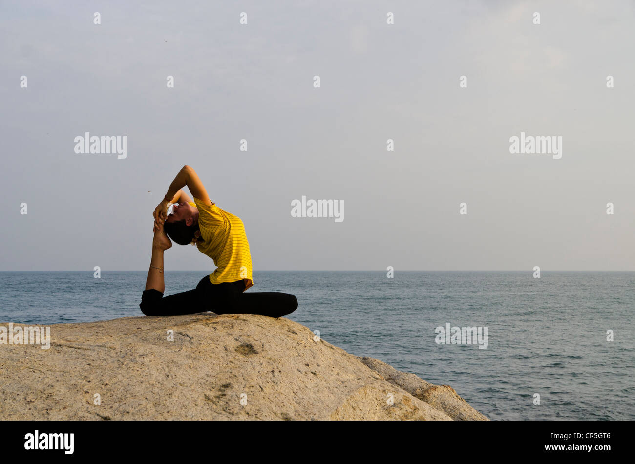Woman in a yoga position, Kapotasana, by the sea in Kanyakumari, Tamil Nadu, India, Asia Stock Photo