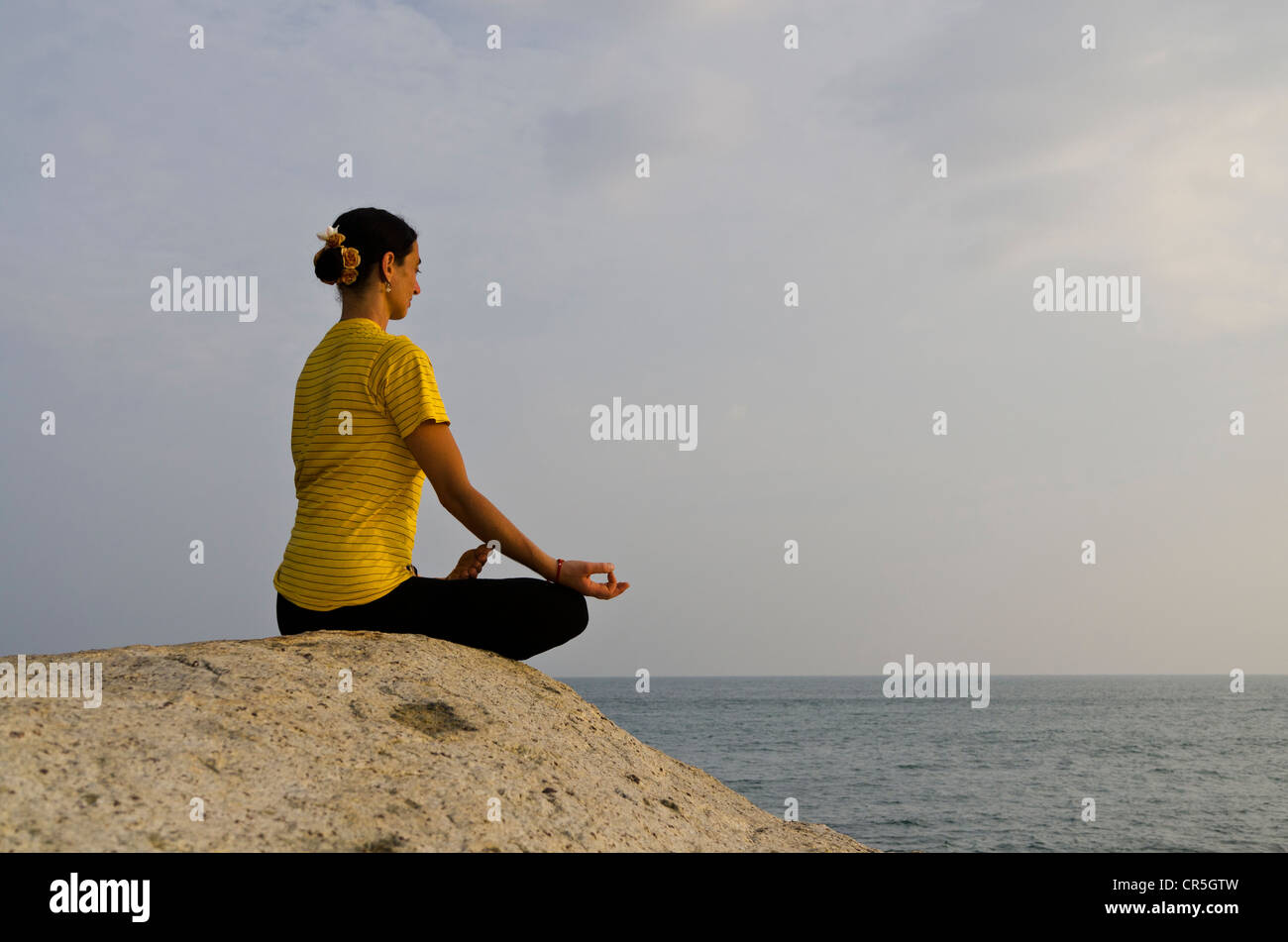 Woman in a yoga position, Padmasana, by the sea in Kanyakumari, Tamil Nadu, India, Asia Stock Photo