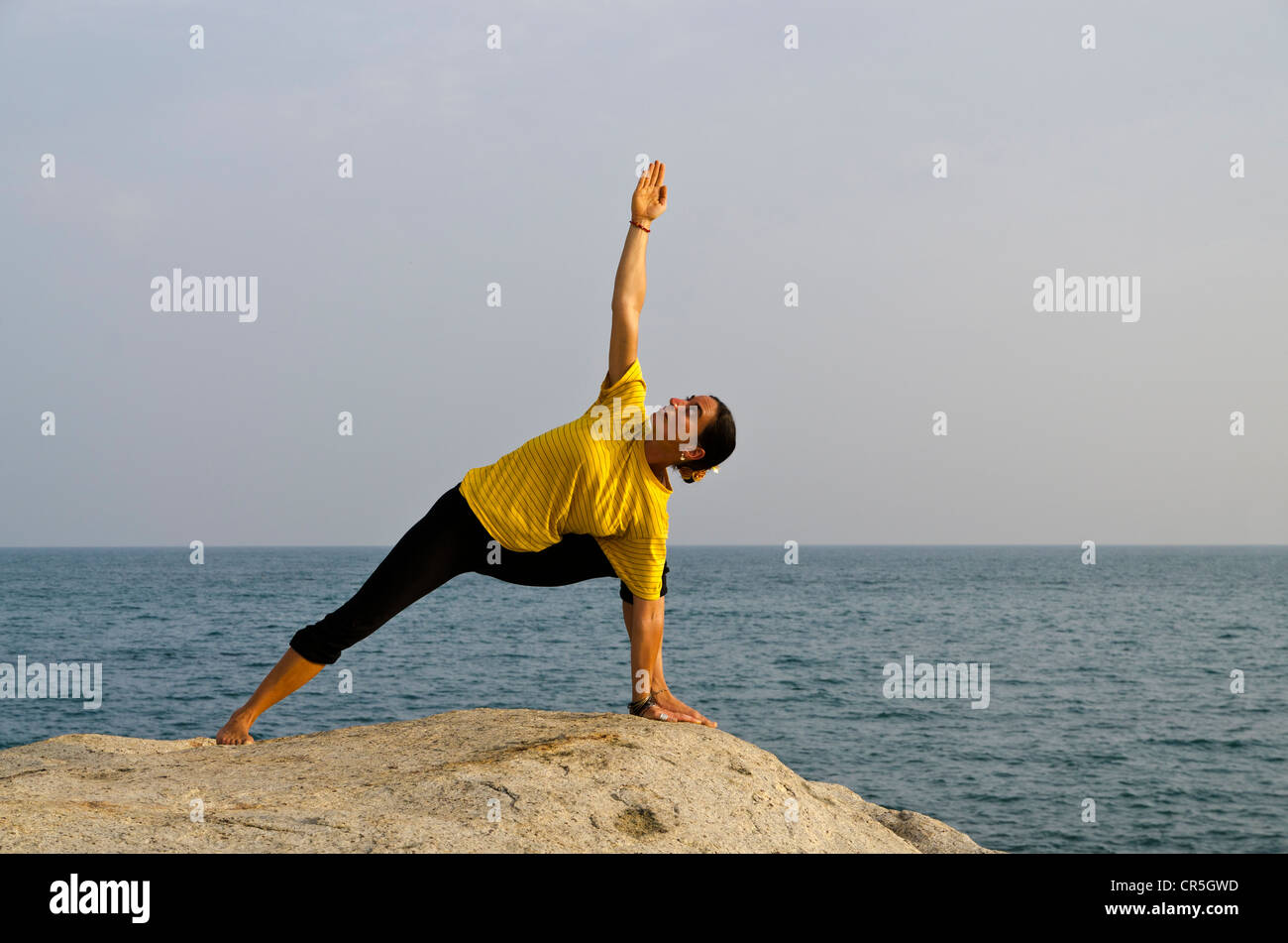 Woman in a yoga position, Utthita-Parshvakonasana, by the sea in Kanyakumari, Tamil Nadu, India, Asia Stock Photo