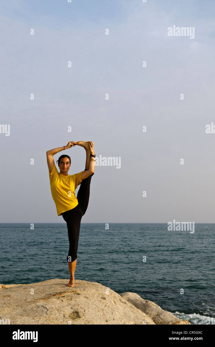 Woman in a yoga position, Anjaneyasana, by the sea in Kanyakumari, Tamil Nadu, India, Asia Stock Photo