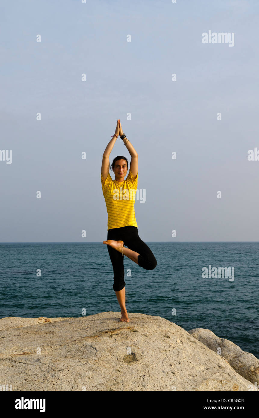 Woman in a yoga position, Vrikshasana, by the sea in Kanyakumari, Tamil Nadu, India, Asia Stock Photo