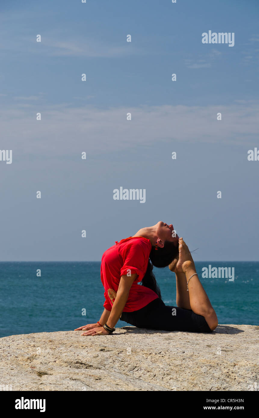 Woman in a yoga position, Bhujangasana, by the sea in Kanyakumari, Tamil Nadu, India, Asia Stock Photo