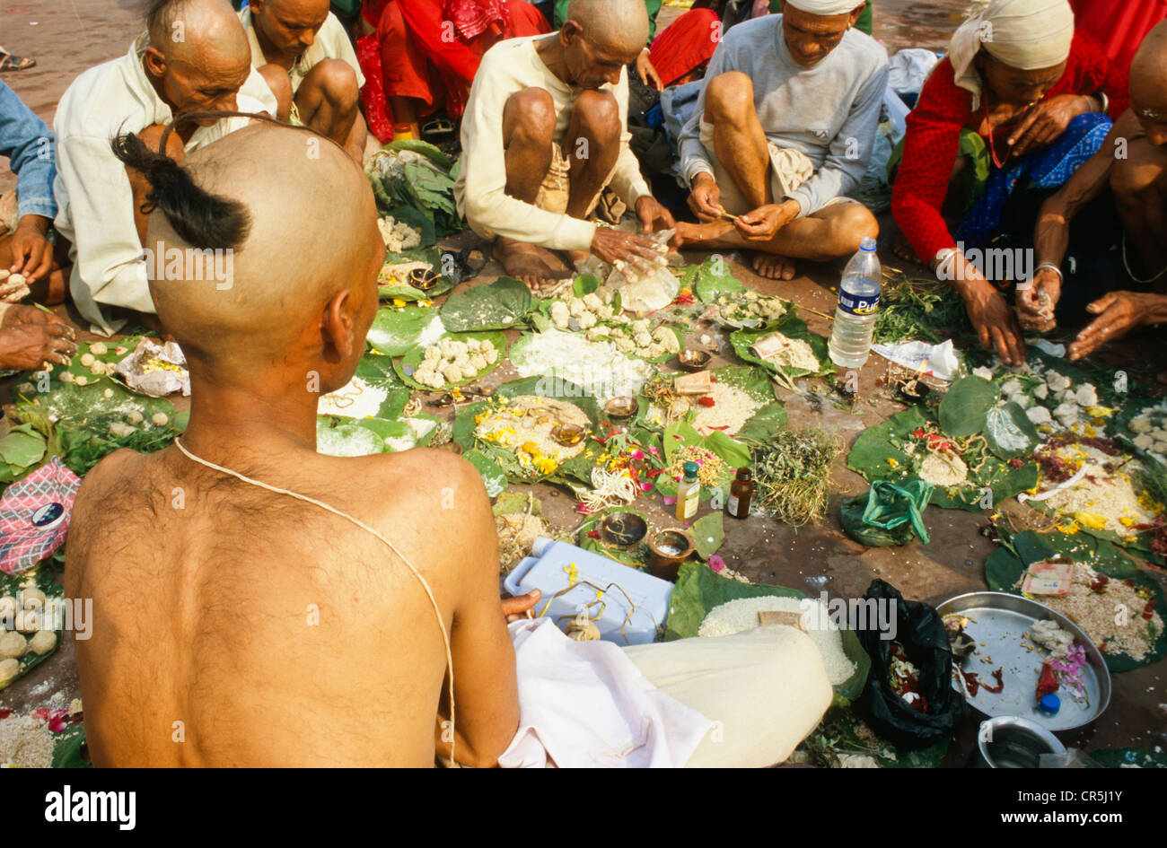 A priest is supporting a praying ritual for the good reincarnation of a dead person at Har Ki Pauri Ghat in Haridwar Stock Photo