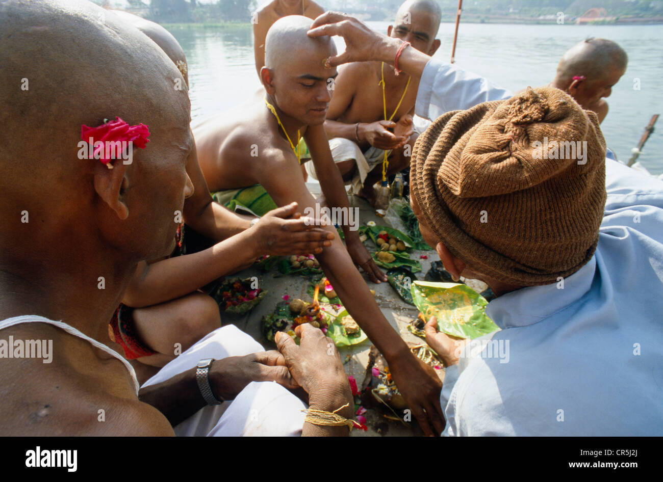A priest is supporting a praying ritual for the good reincarnation of a dead person at Har Ki Pauri Ghat in Haridwar Stock Photo