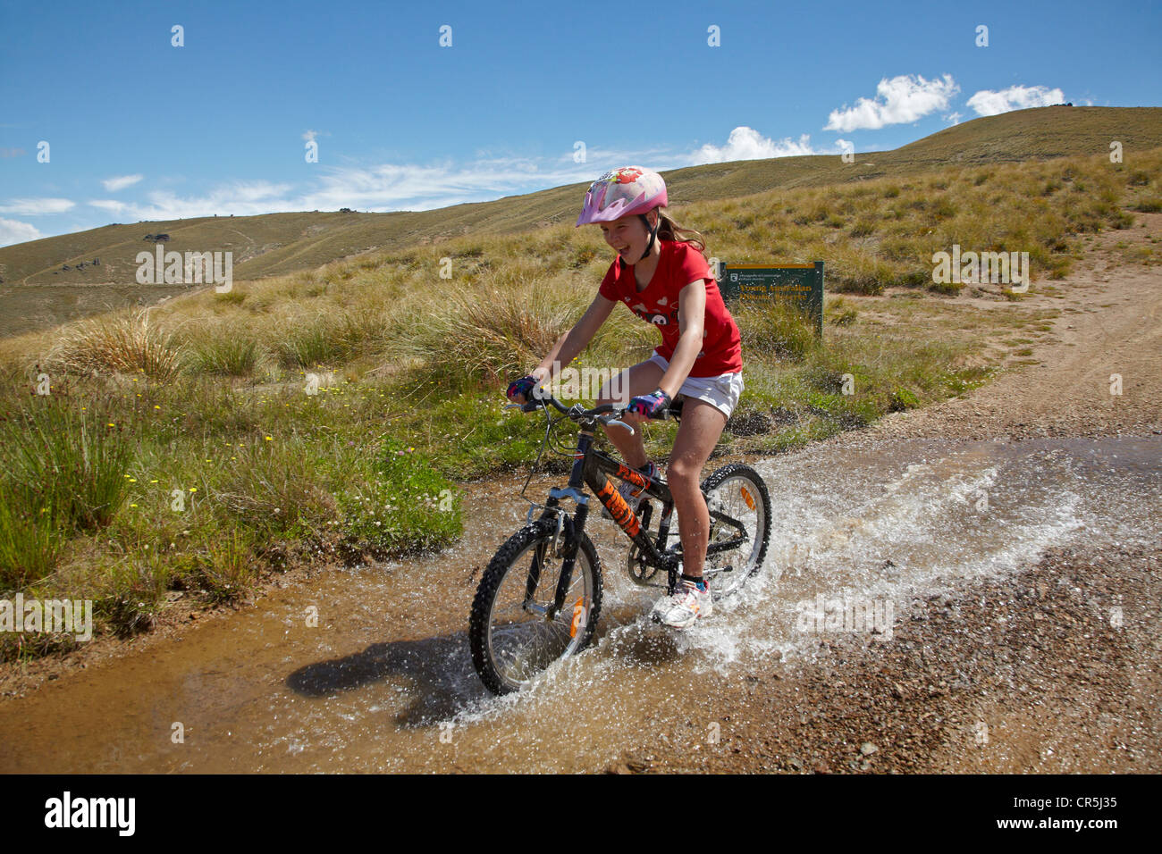 Young mountain biker riding through water race, Carrick Track, Carrick Range, Central Otago, South Island, New Zealand Stock Photo