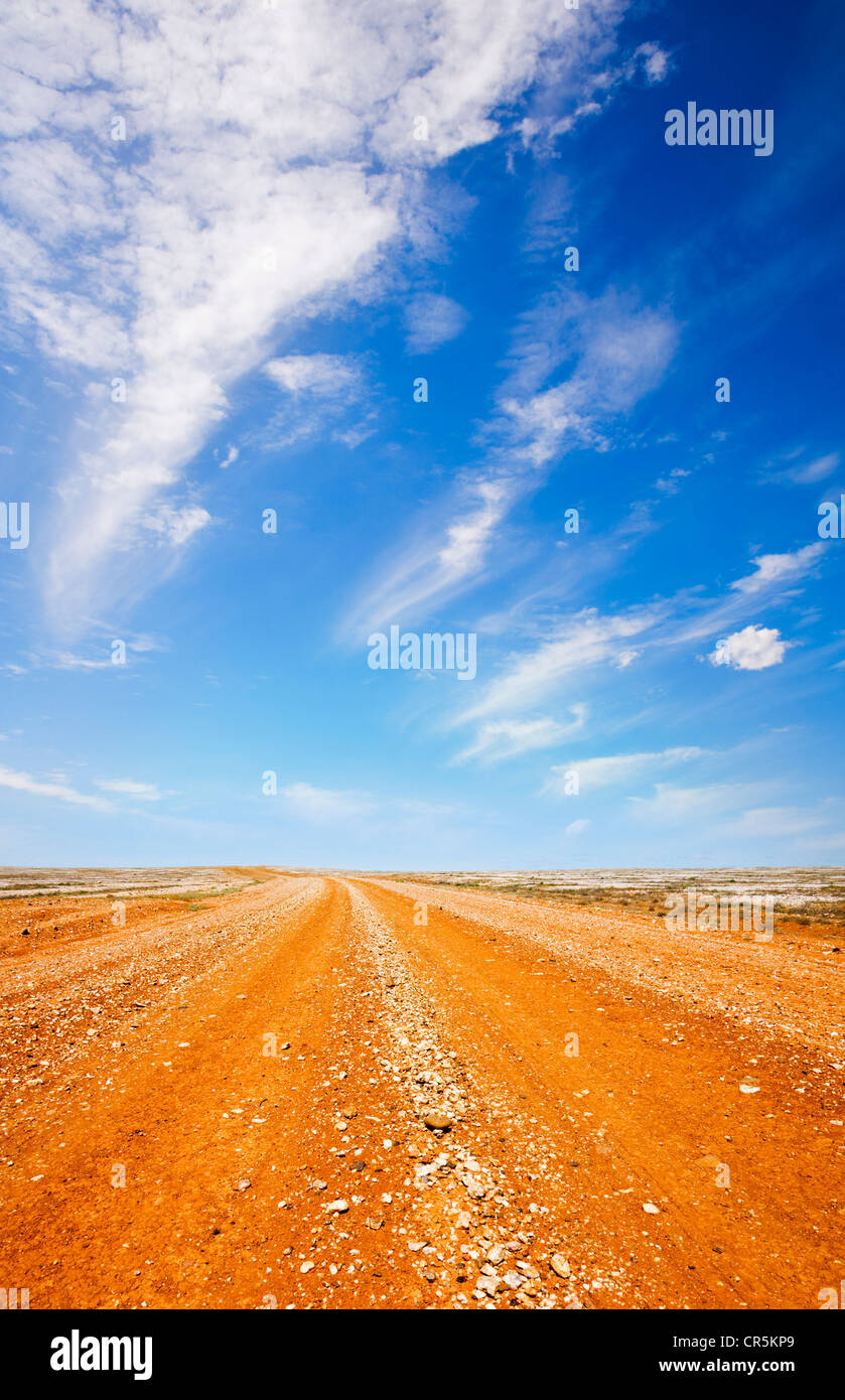 Red dirt road in the Australian outback, under a blazing hot blue sky