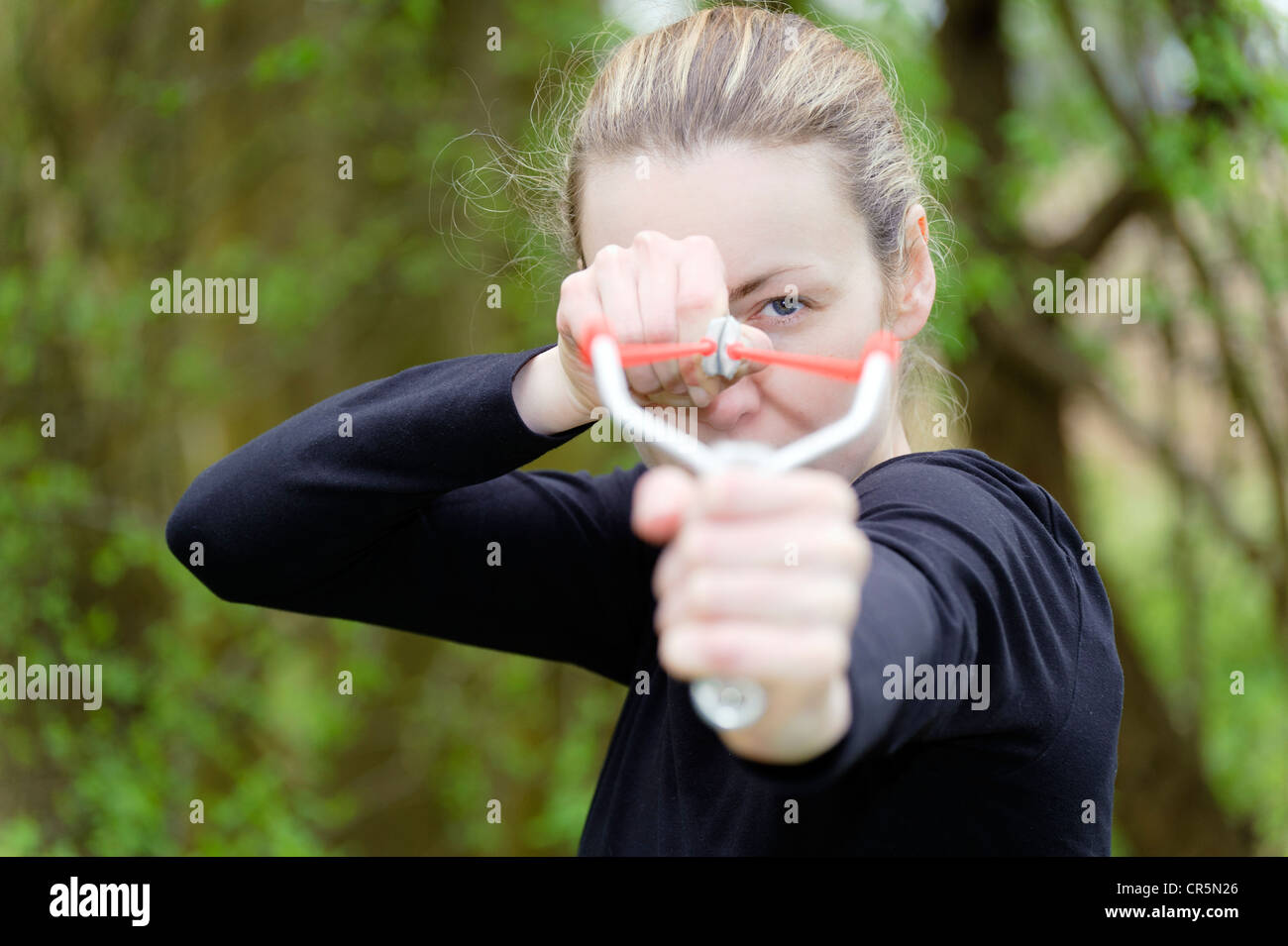 Young woman aiming a catapult, slingshot Stock Photo