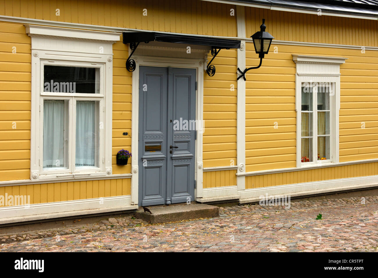Yellow ocher facade of a traditional Finnish log house with windows and entrance door, old town of Porvoo, Finland, Europe Stock Photo