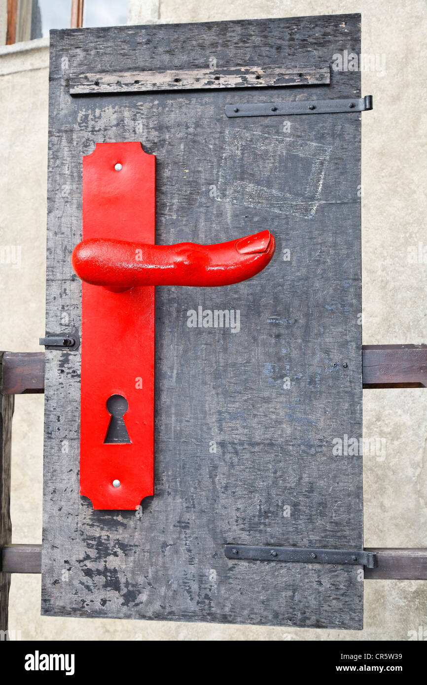 Door handle shaped as a finger on an old wooden door, artwork, Cesky