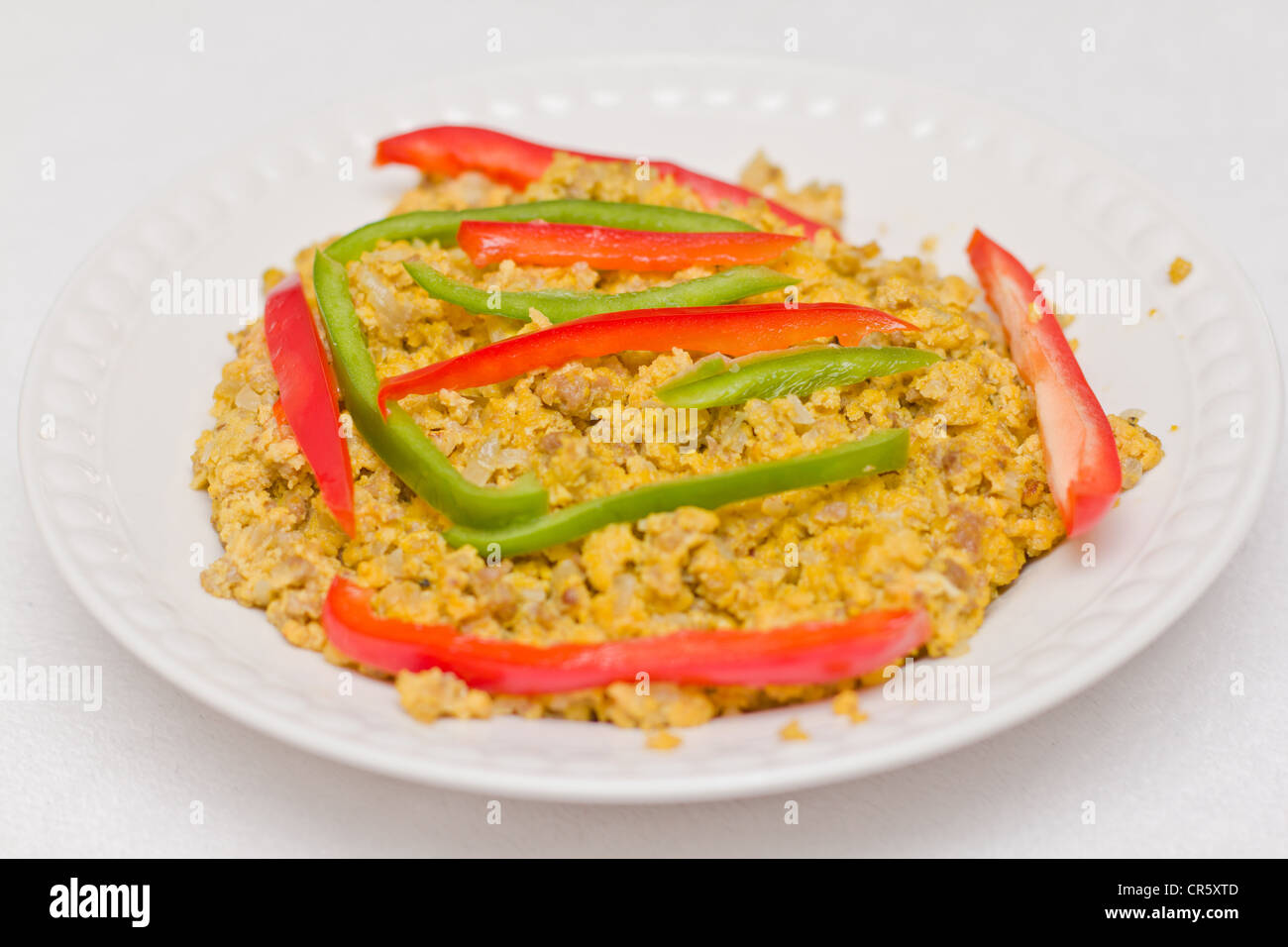 Scrambled eggs served on a plate with sliced bell peppers Stock Photo