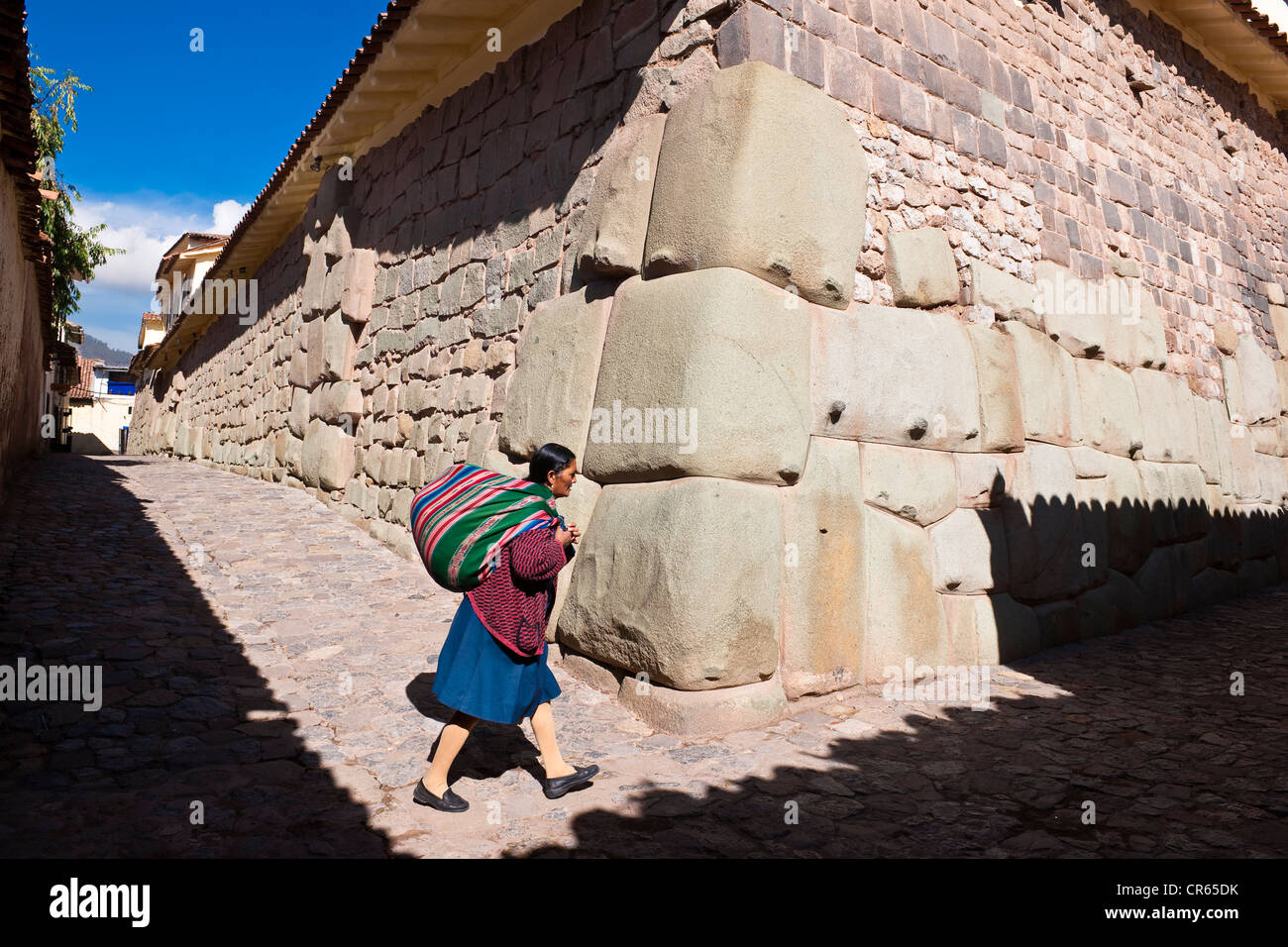 Peru, Cuzco Province, Cuzco, UNESCO World Heritage, Calle Hatun Rumiyoc, Quechua Indian in front of a remain of an Inca wall Stock Photo