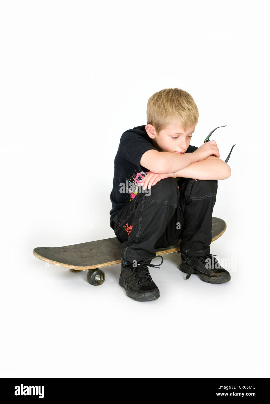Studio image of Caucasian 8 year old boy with skateboard on a white background looking fed up Stock Photo