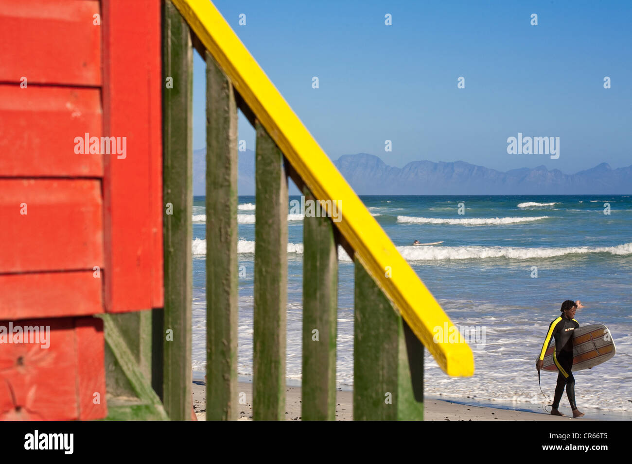 South Africa, Western Cape, Cape Town, on the road of the Cape Peninsula, Muizenberg, beach cabin and surfer Stock Photo