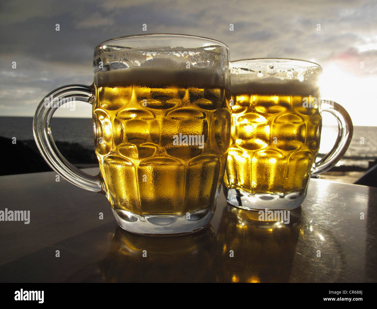 Spain, Two beer glasses on table with sea in background Stock Photo