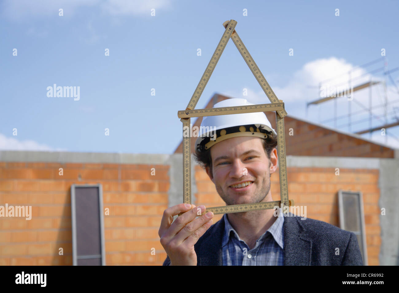 Germany, Bavaria, Young man with hard hat showing pocket rule at ...