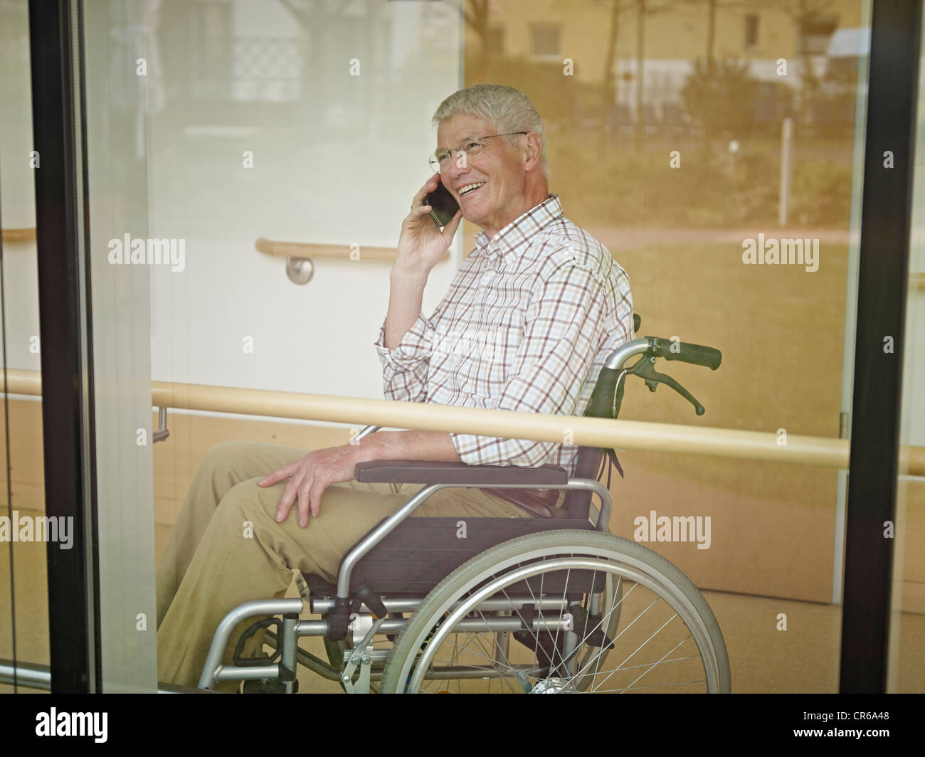 Germany, Cologne, Senior man on phone in nursing home, smiling Stock Photo