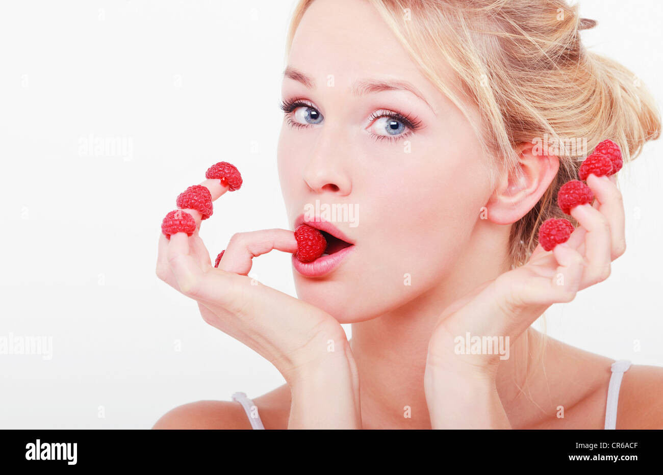 Young woman with raspberries on her fingertips, portrait Stock Photo