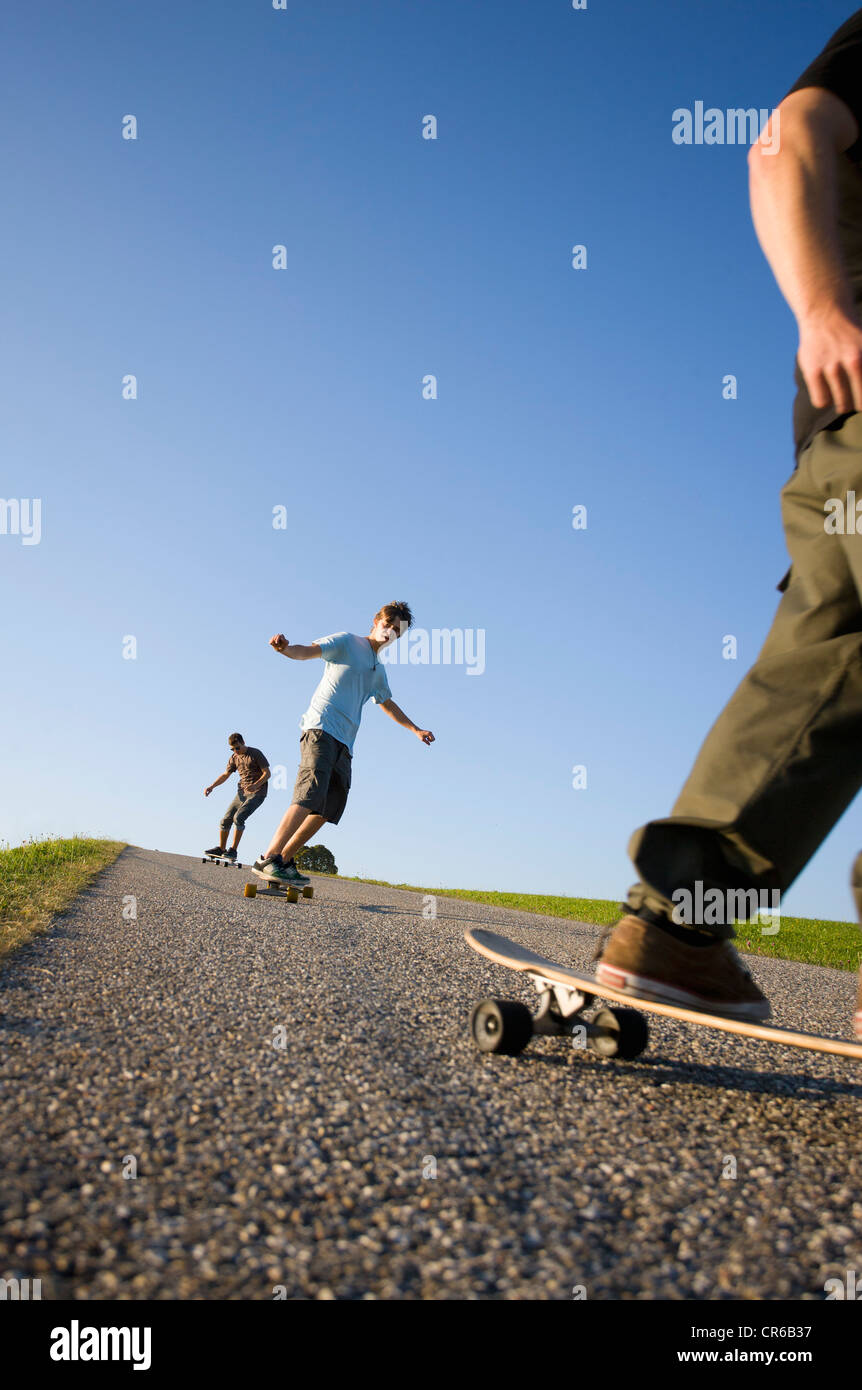 Austria, Young men doing longboarding on road Stock Photo