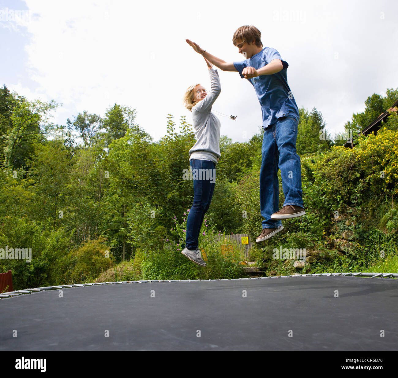 Austria, Young man and woman jumping on trampoline Stock Photo