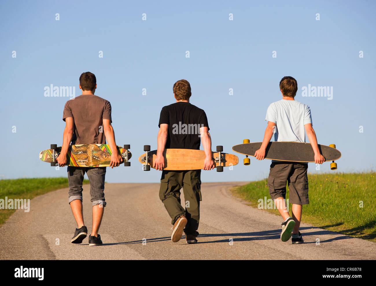 Austria, Young men with skateboard on road Stock Photo