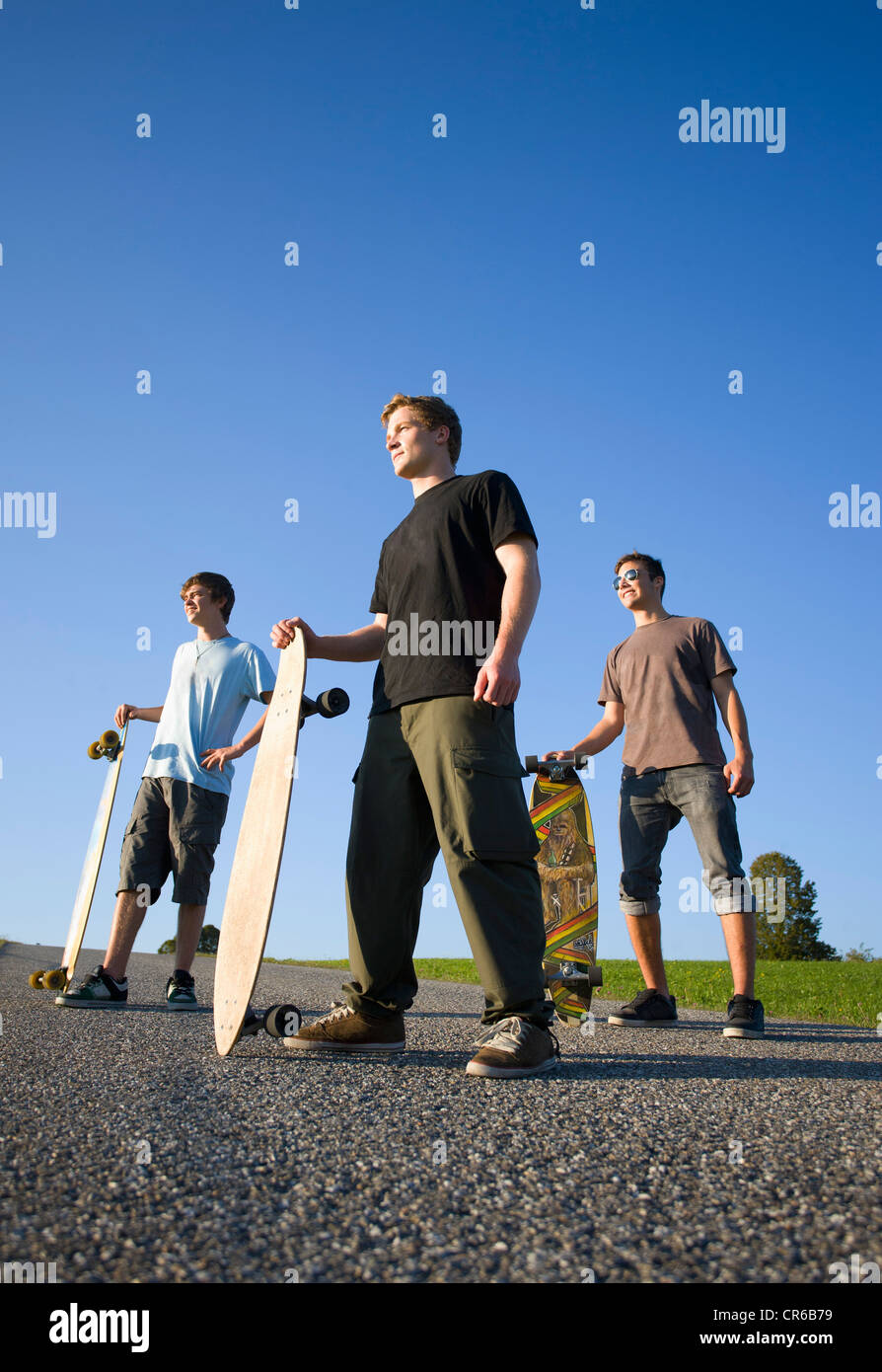 Austria, Young men with skateboard on road Stock Photo