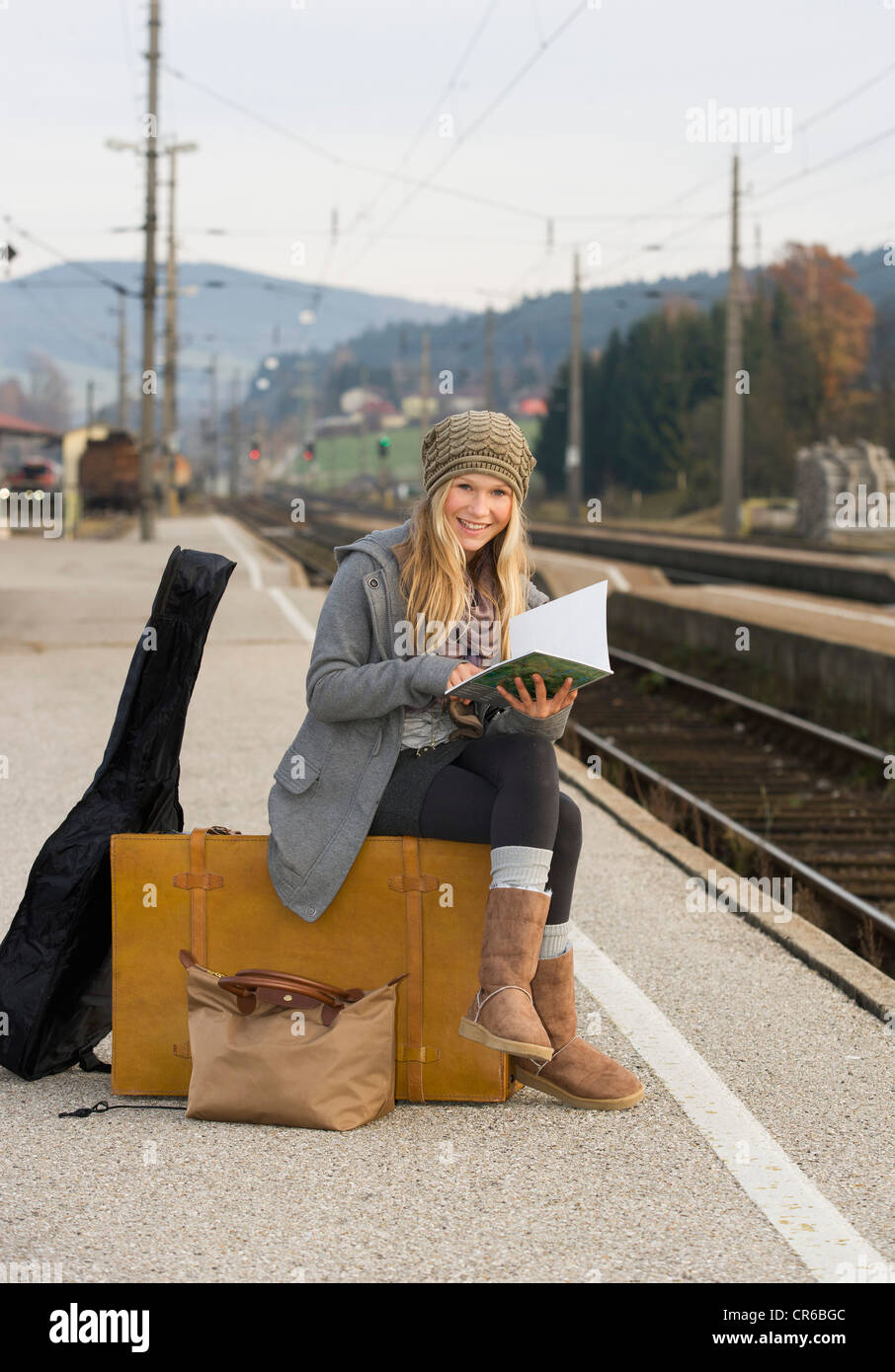 Austria, Teenage girl with suitcase on train station Stock Photo