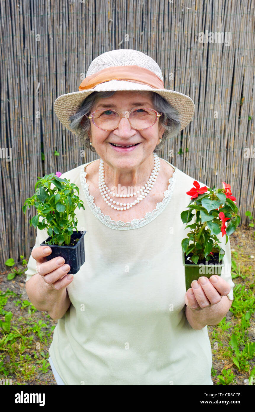 Happy senior woman holding flowers in garden Stock Photo - Alamy