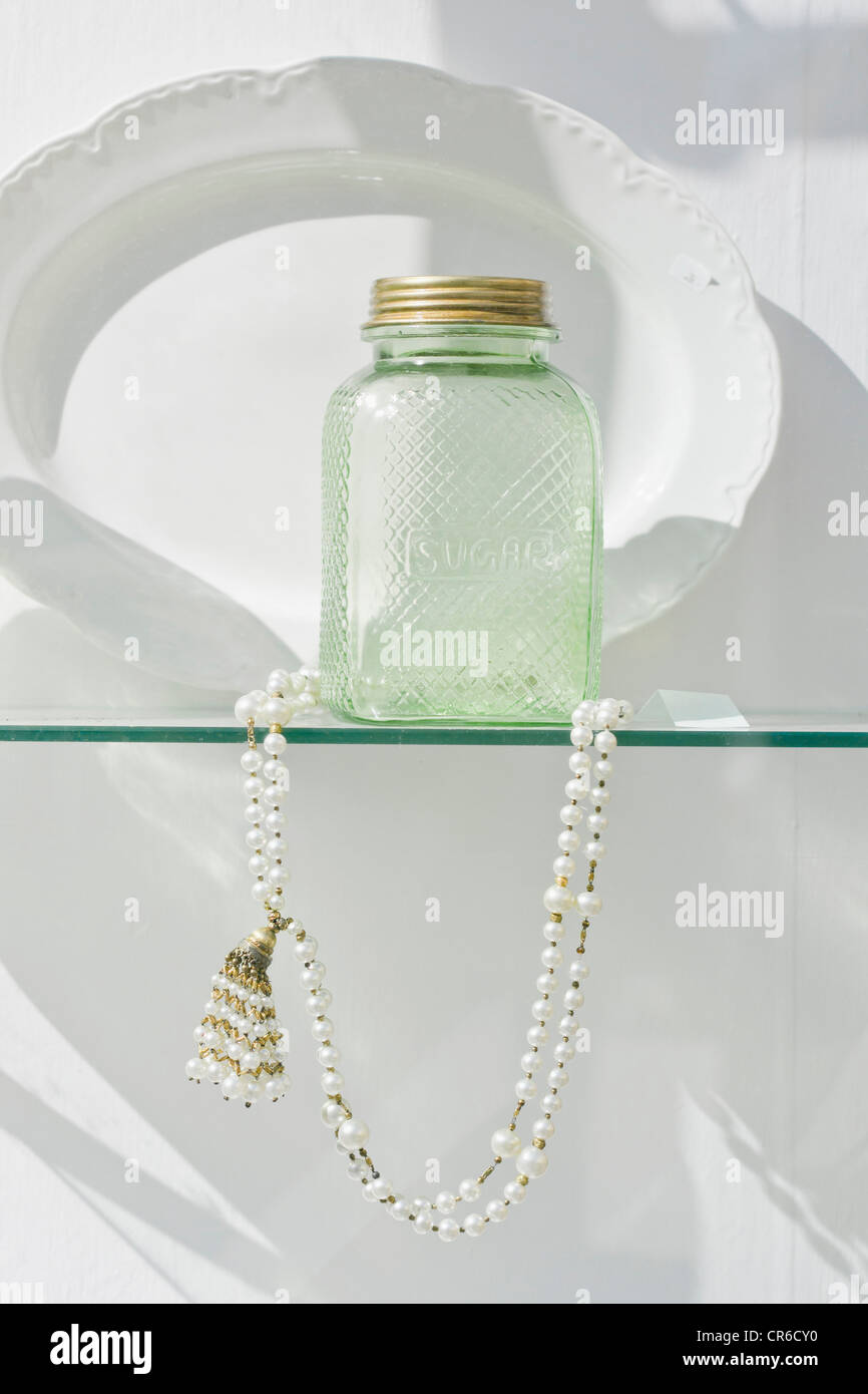 Germany, Bavaria, Munich, Old sugar bottle with pearl necklace behind display window Stock Photo